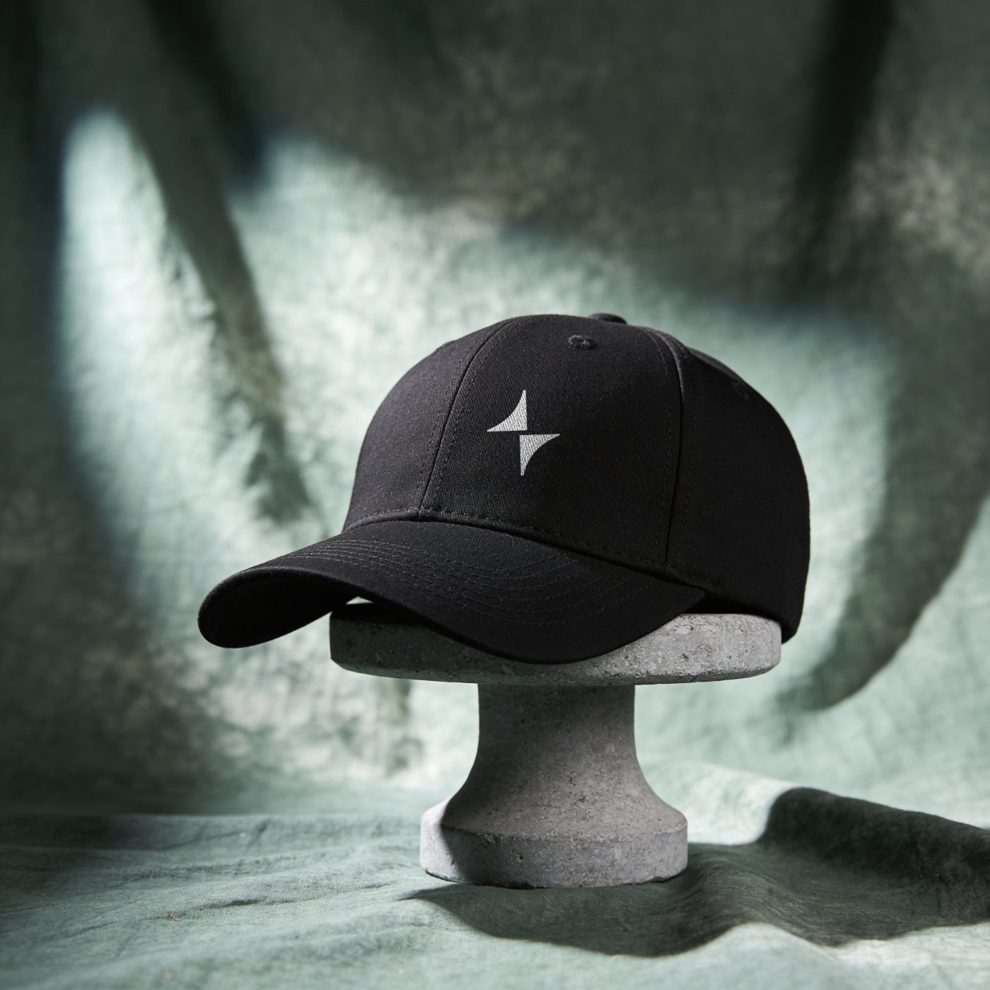 Black cap with a small white spark on a stone stand