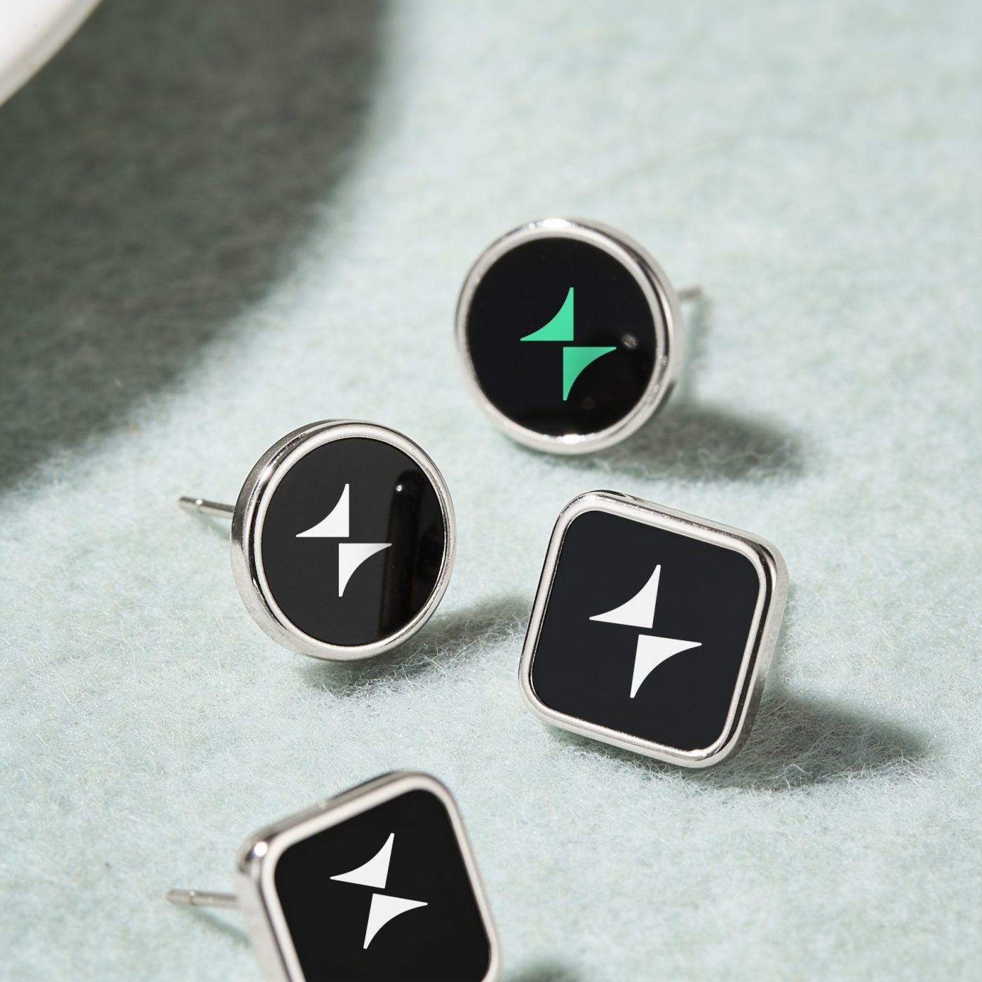 Four enamel pins with the spark, one in glow green