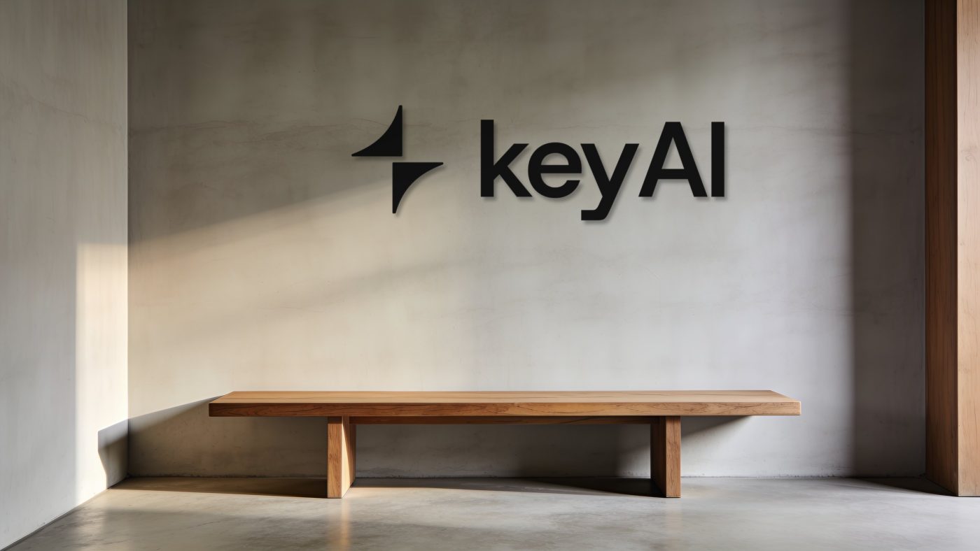 Calm reception with a matte black keyAI lockup on a grey plaster wall above an oak bench