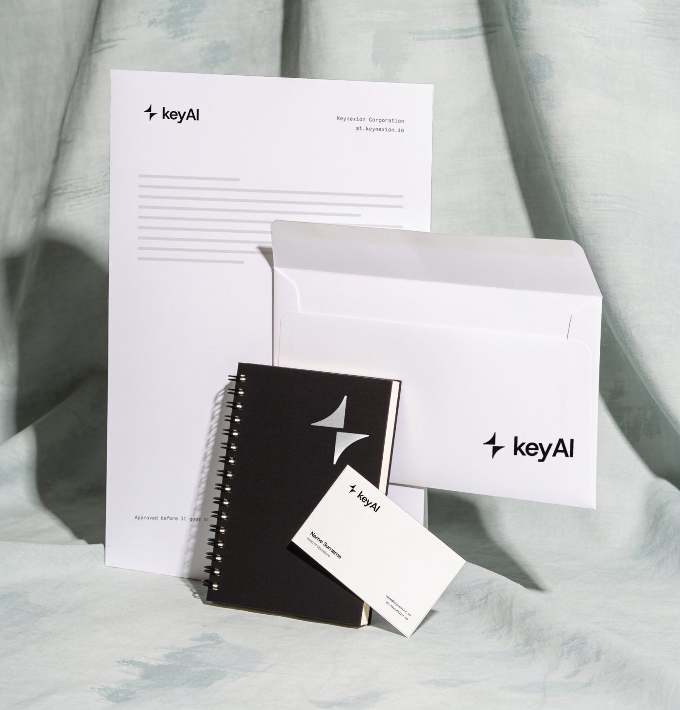 Letterhead, envelope, black notebook and business card with the keyAI logo on a pale mint backdrop